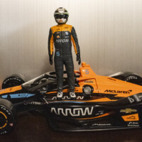 A photo of a model car and a figurine of the car's driver standing on top of it.