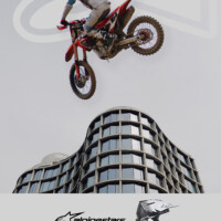 A dirtbike rider jumping over a building with a grey sky for an Alpinestars print ad.