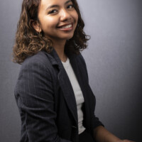 A business portrait of a woman in a blazer smiling and leaning back towards her right