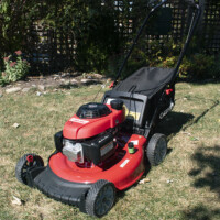 A photo of a new lawnmower in a backyard on a sunny day.